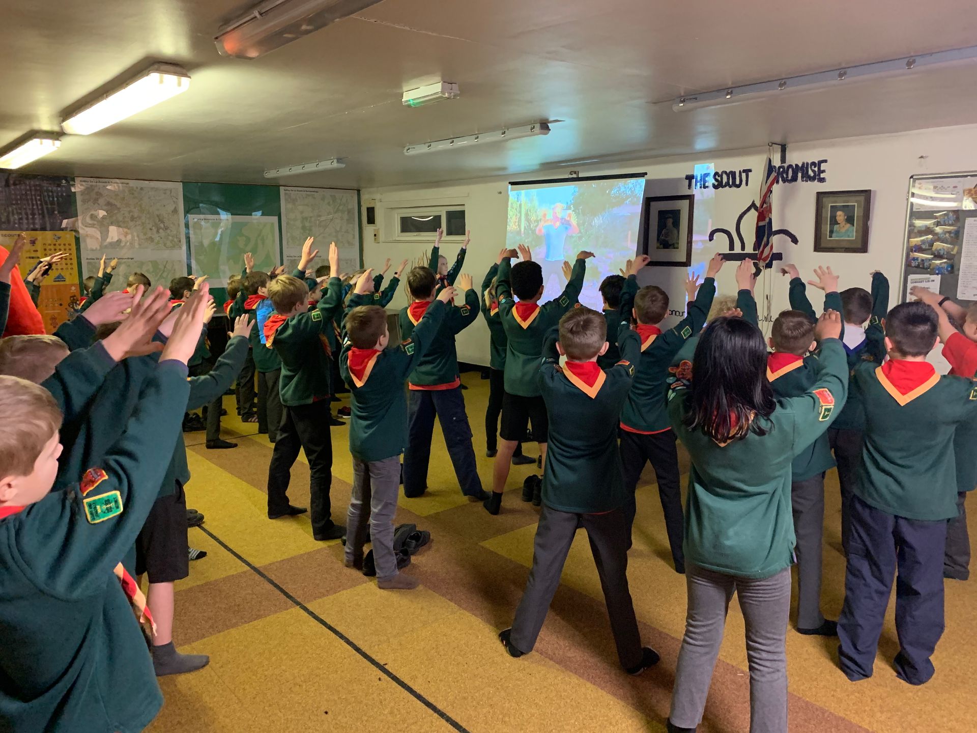 A group of children are standing in a room with their hands in the air.