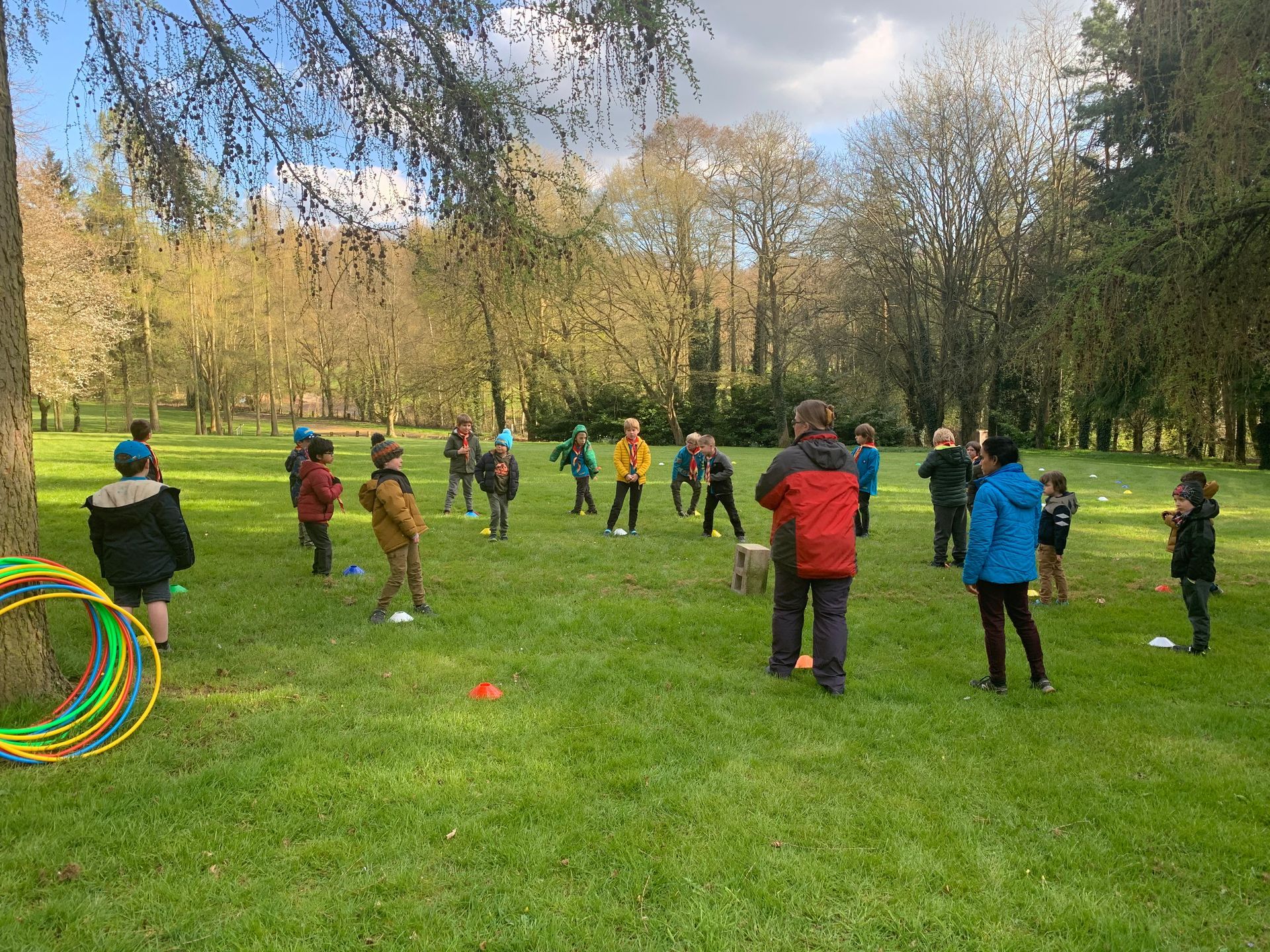 A group of children are playing in a park with hula hoops.