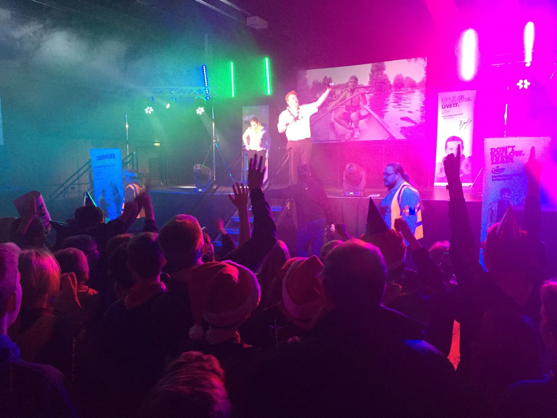 A crowd of people are standing in front of a stage at a concert.