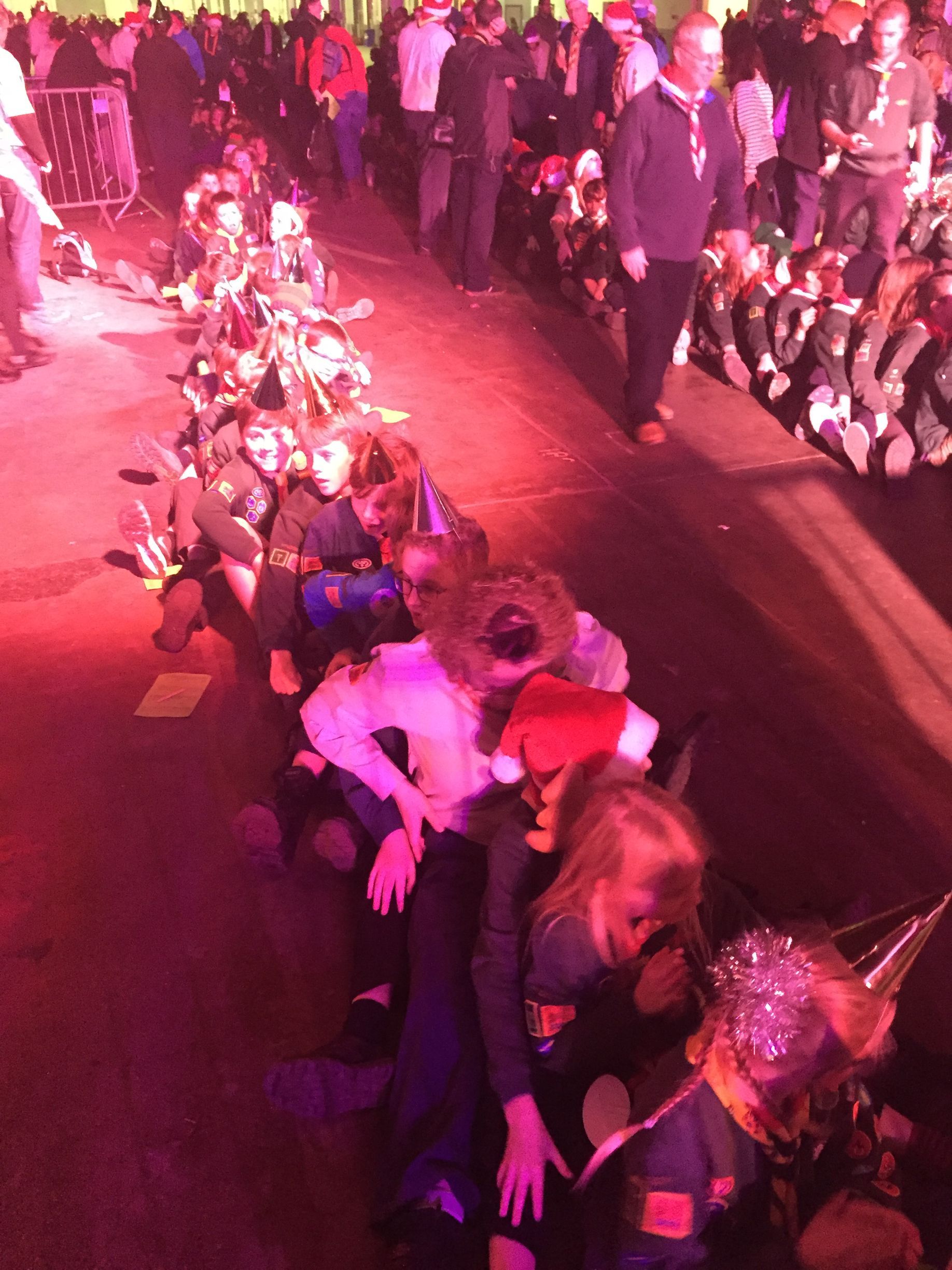 A group of people are sitting on the floor in a dark room