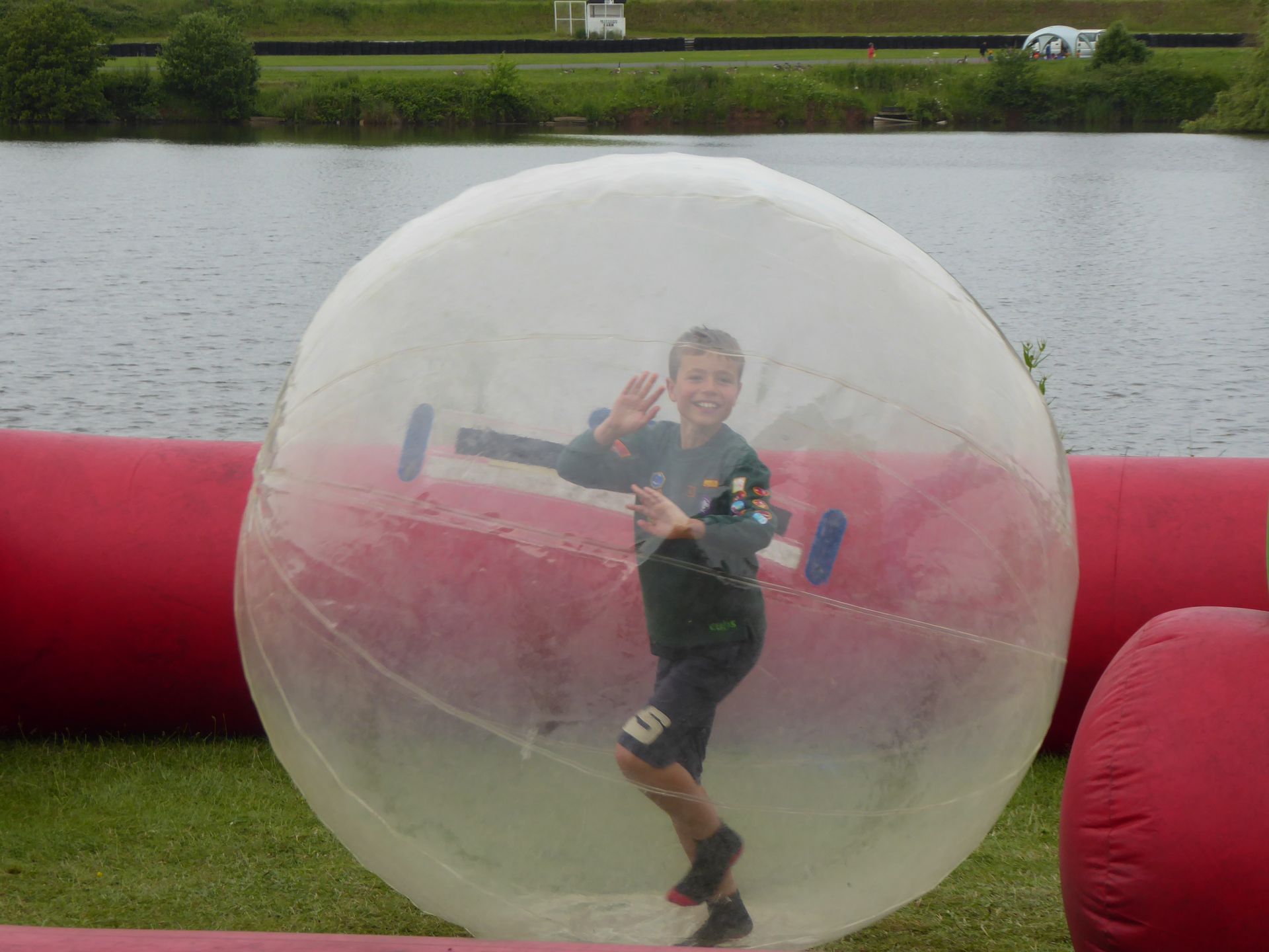 A young boy is standing inside of a water walking ball.
