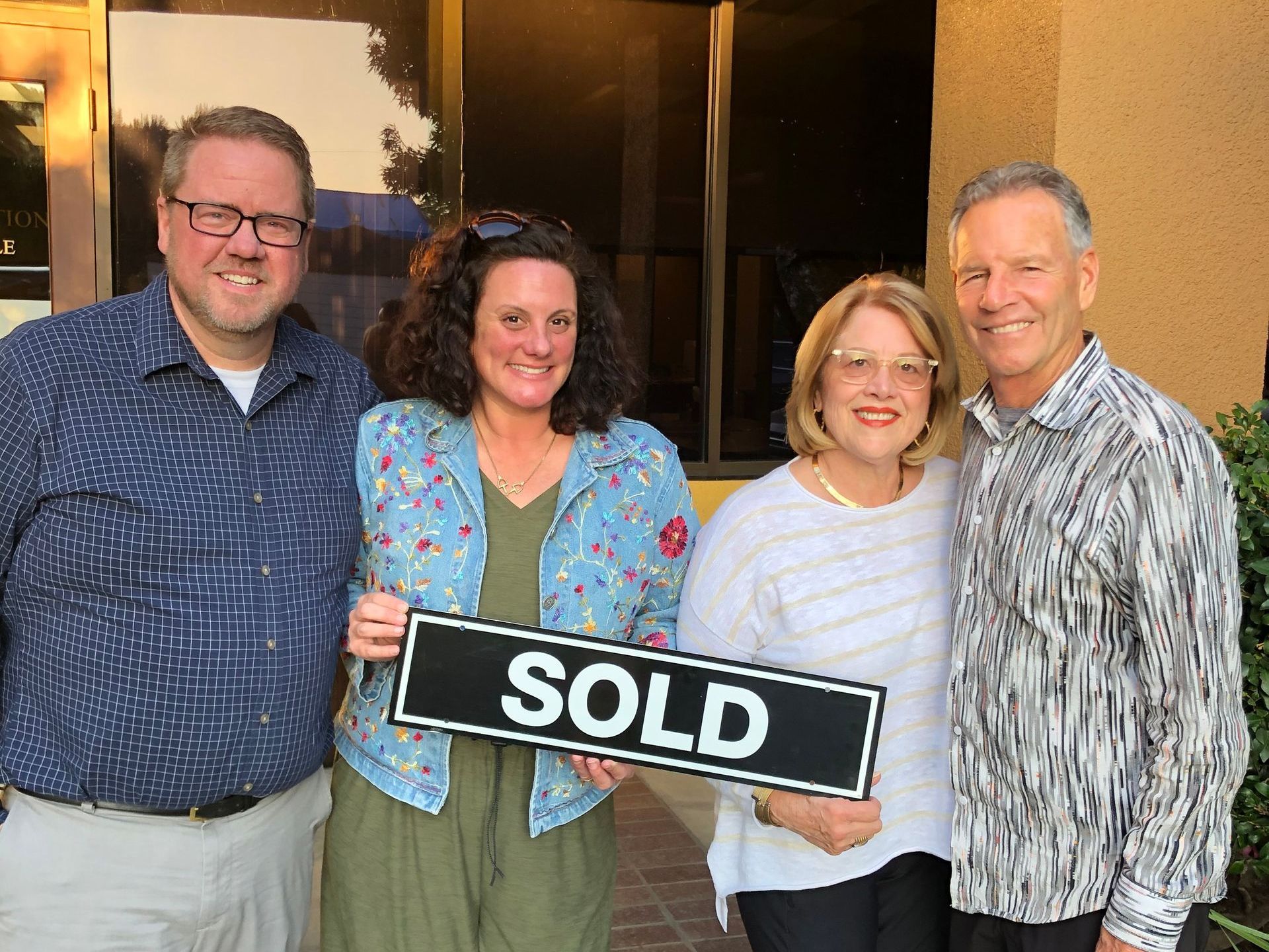 Donna and Barney with a husband and wife home sellers  holding a sold sign