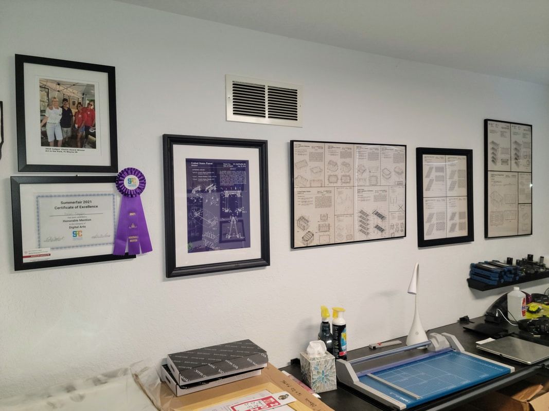 Office wall with framed certificates and documents above a desk and equipment