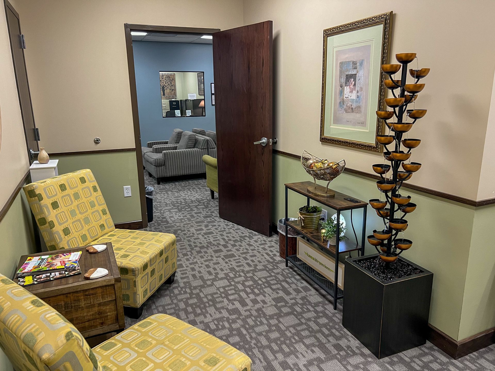 A waiting room with chairs , a table and a fountain.