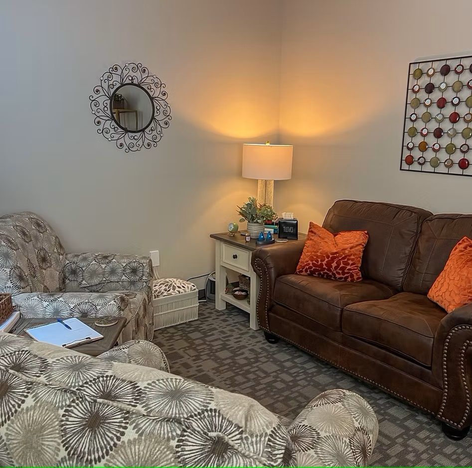 A living room with a brown couch and orange pillows