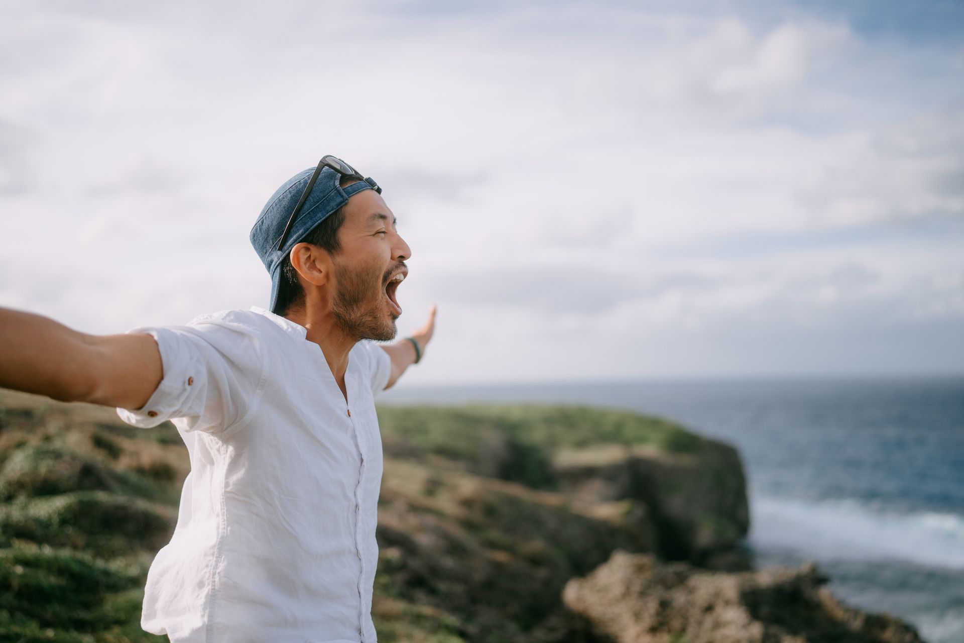 A man is standing on top of a cliff with his arms outstretched. A man is standing on top of a cliff with his arms outstretched.