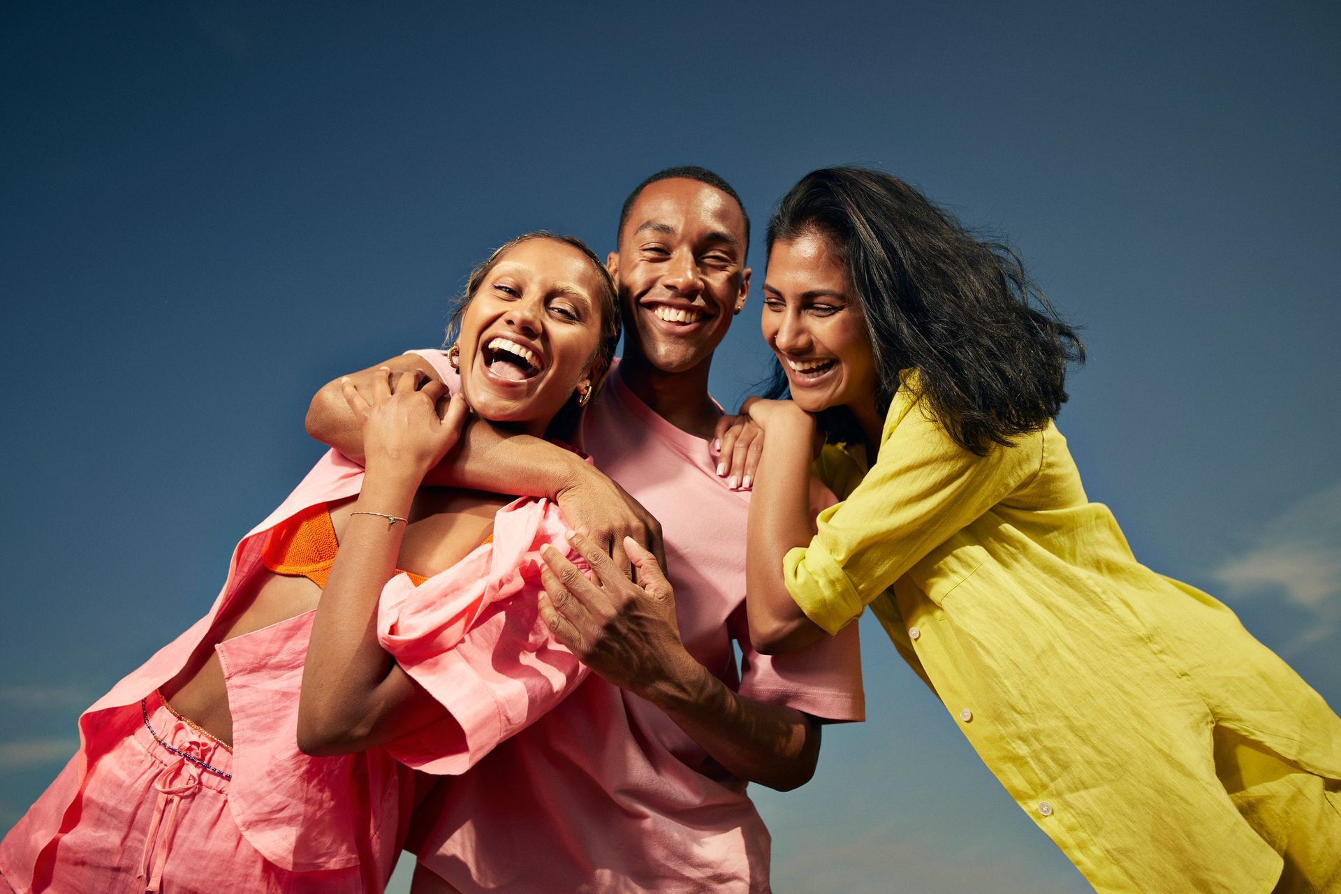 A man and two women are hugging each other on a beach.