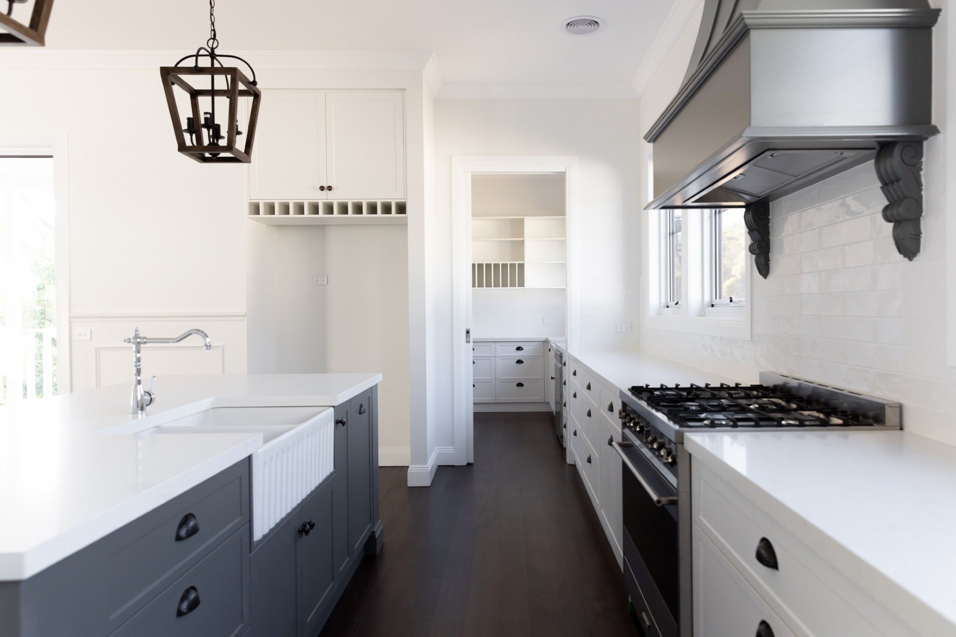 Modern white kitchen with gray island and dark wood floor.