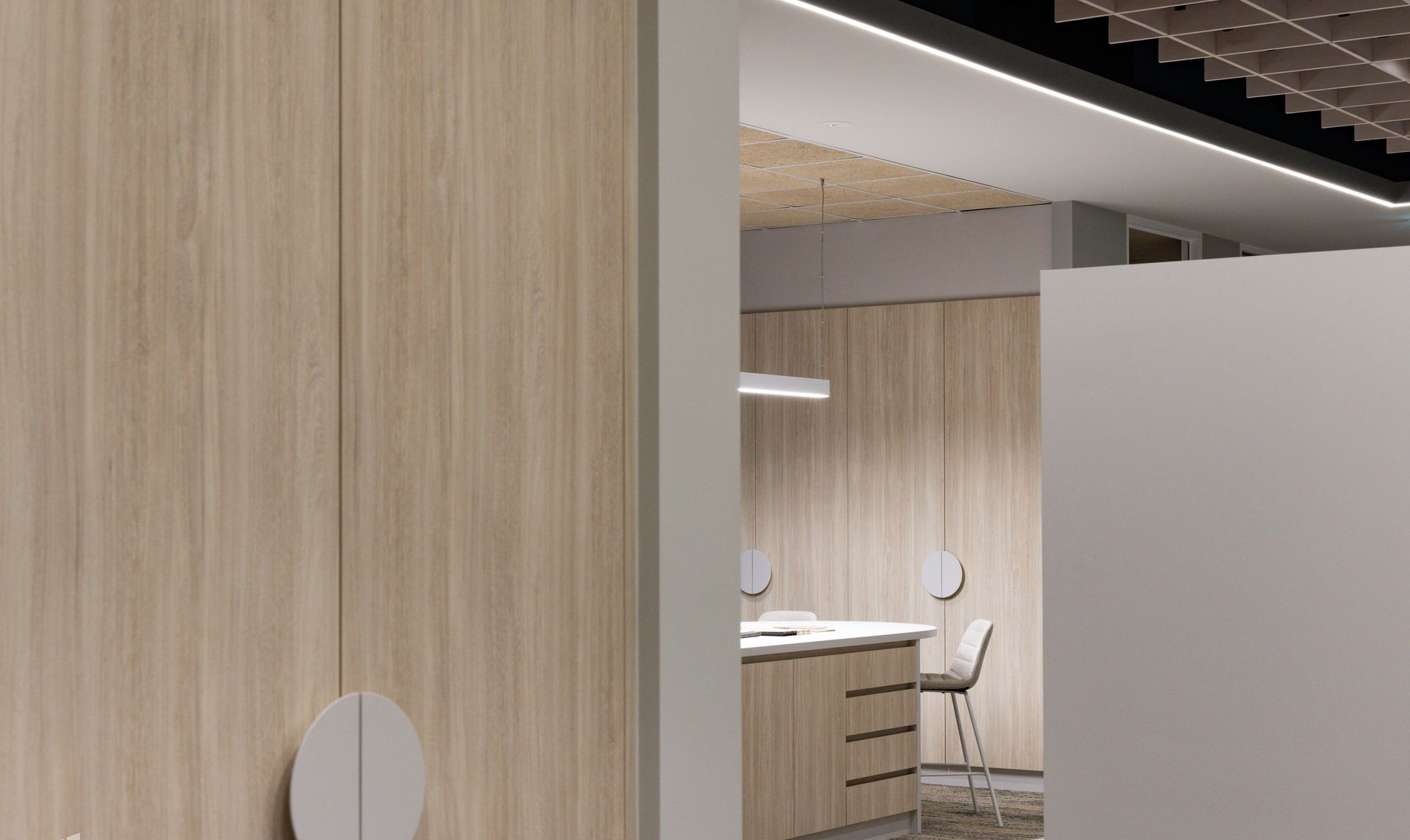 Light wood cabinets and a desk in a modern interior, seen through a doorway.