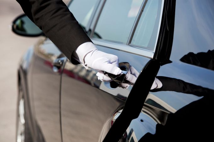 Mano guantata che pulisce la maniglia della portiera di un'auto nera con un panno