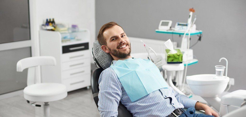 Smiling man in dentists chair waiting on dental procedure