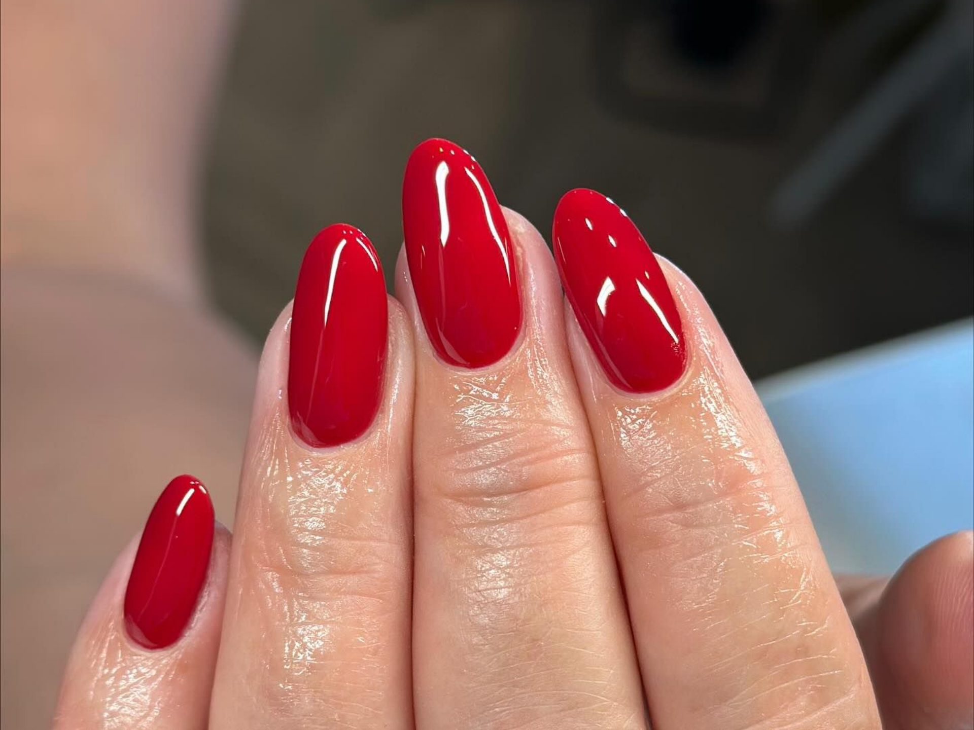Hand with red, glossy, oval-shaped nails.