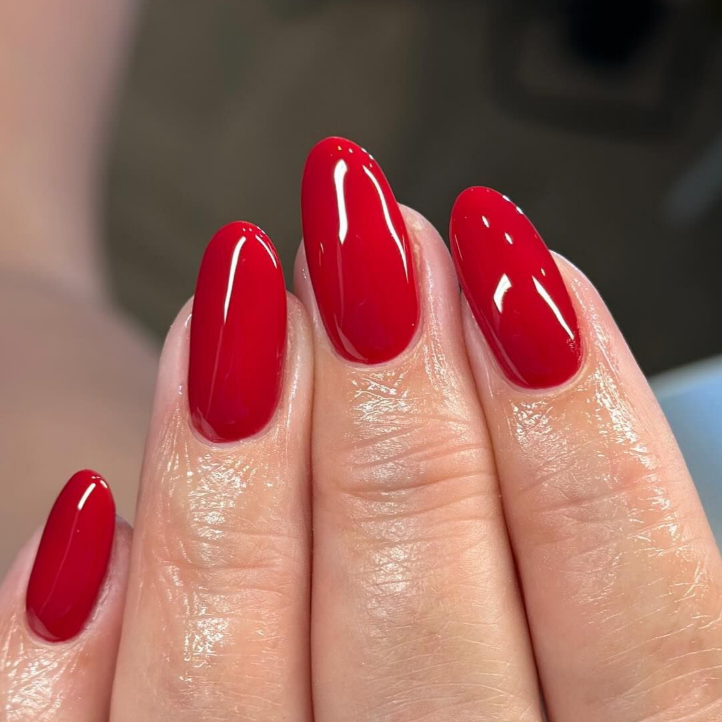 Hand with red, glossy, oval-shaped nails.