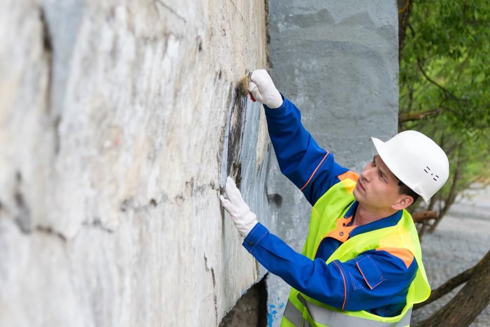 Man Wearing a Hard Hat and Safety Vest is Working on a Wall — Capital Ultimate Facility in Queanbeyan, NSW