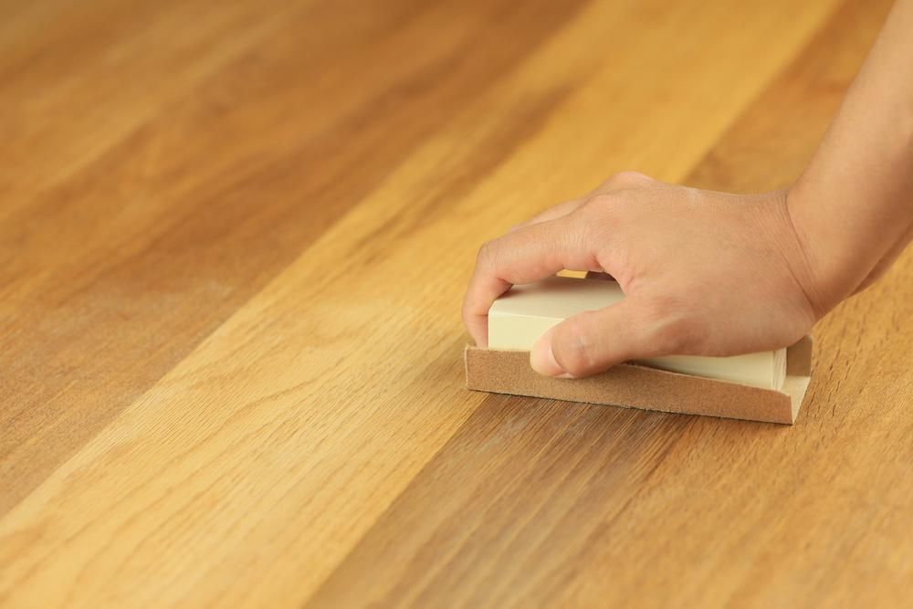 Person is Sanding a Wooden Surface With a Sanding Block — Capital Ultimate Facility in Tuggeranong, ACT