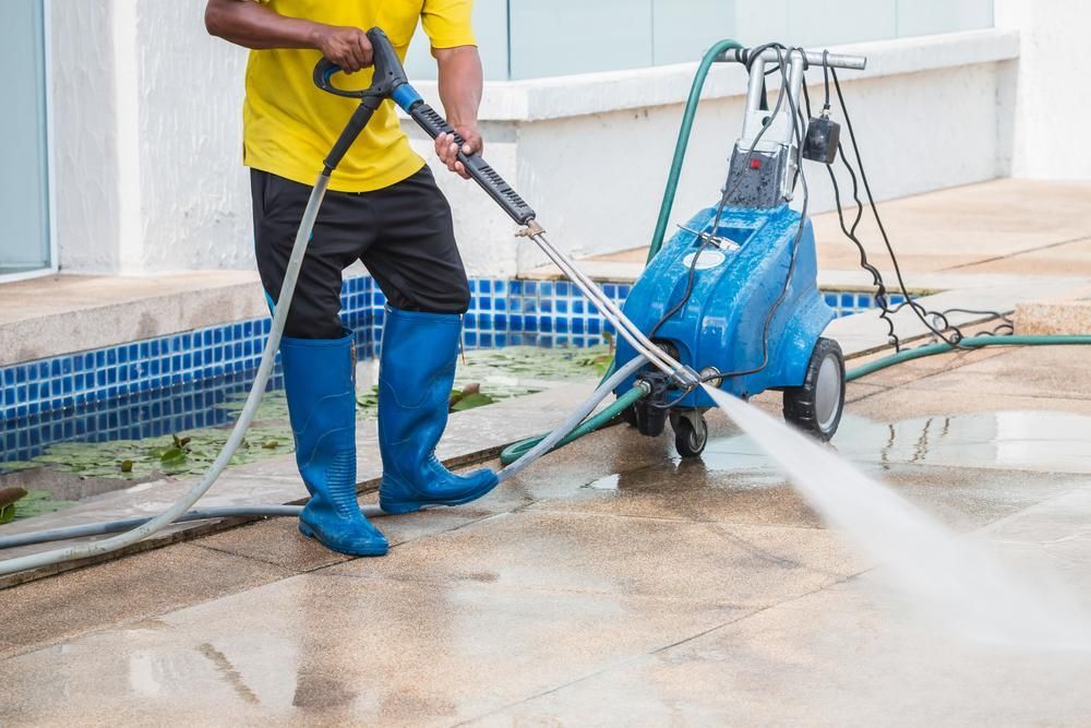 Man is Cleaning the Sidewalk With a High Pressure Washer — Capital Ultimate Facility in Belconnen, ACT