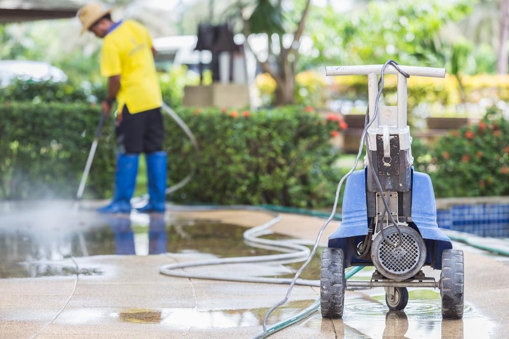 Man is Using a High Pressure Washer to Clean a Concrete Floor — Capital Ultimate Facility in Beard, ACT