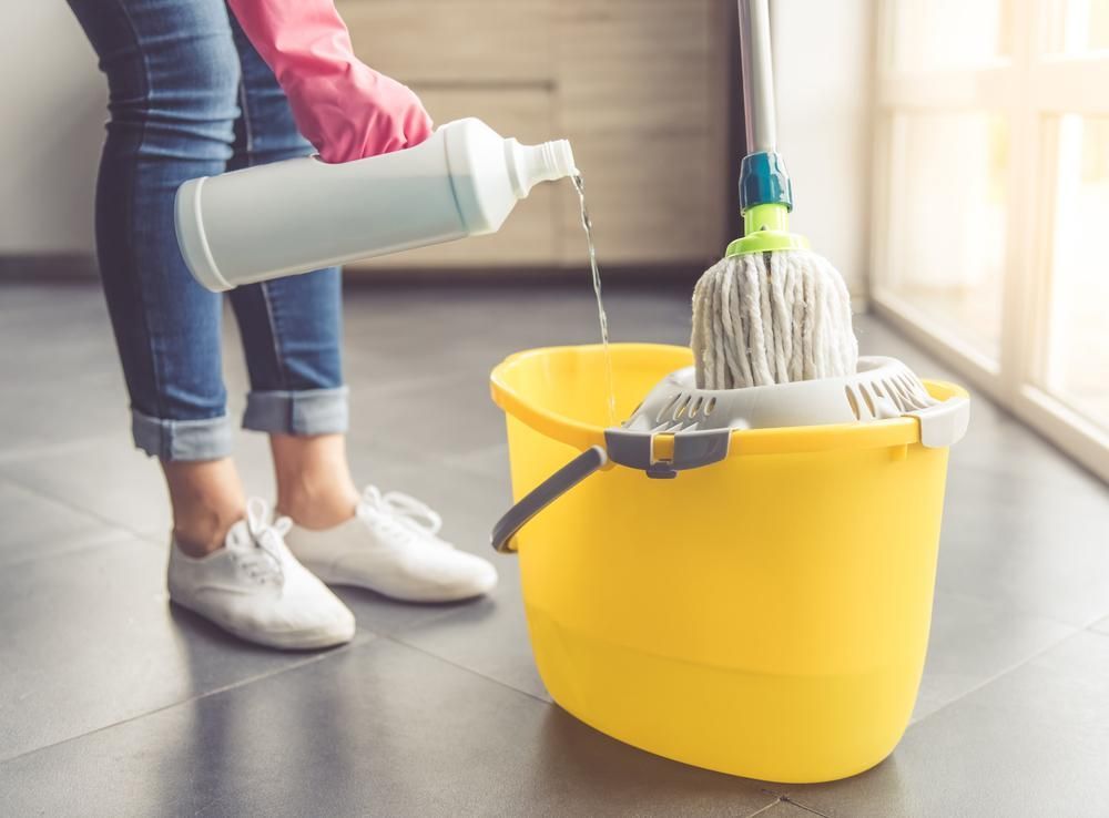 Woman is Pouring Cleaner Into a Mop in a Yellow Bucket — Capital Ultimate Facility in Gungahlin, ACT