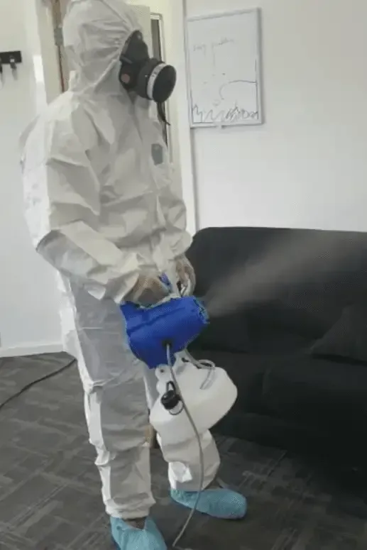 A person in a protective suit is spraying a room with a sprayer. — Capital Ultimate Facility in Beard, ACT
