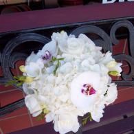 White floral bouquet with a pink orchid on a burgundy bench rail