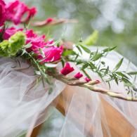 Pink flowers and sheer white fabric draped over a wooden structure outdoors