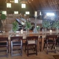 Rustic bar with wooden stools, potted plants, and a bright doorway in a thatched-roof room