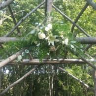 White flowers on a wooden trellis in a lush green garden.