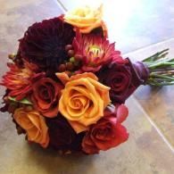 Bouquet of red, orange, and yellow roses on a tiled surface