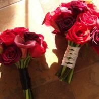 Two bouquets of red roses with white ribbons on a sunlit surface