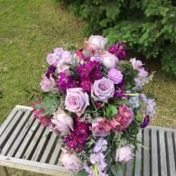 Purple and pink flower bouquet on a bench outdoors
