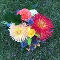 Colorful bouquet of mixed flowers on green grass, featuring pink, red, yellow, white, and blue blooms