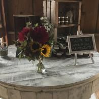 Rustic table with a bouquet of flowers and a small chalkboard sign in a cozy indoor setting