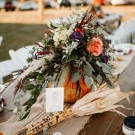 Floral centerpiece with roses and greenery on a rustic table set for an event
