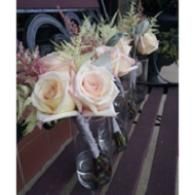 Pale pink roses and greenery arranged in a bouquet on a railing