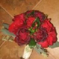 Red rose bouquet with green leaves on a beige tiled background