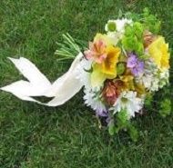 White ribbon tied to a colorful flower bouquet on grass