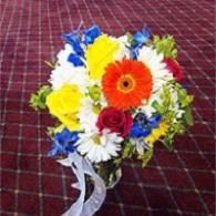 Colorful bouquet of mixed flowers with blue, yellow, white, and orange blooms on a patterned cloth