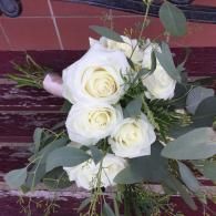 White rose bouquet with greenery on a patterned red tablecloth