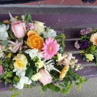 Mixed bouquet of pink, yellow, and white flowers with greenery on a rustic wooden surface