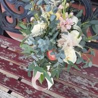 Bouquet of pastel flowers and greenery in a white jug on a weathered red bench
