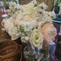 White and pale pink floral bouquet in a glass vase with ribbon, arranged on a table