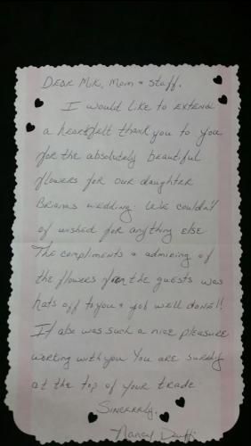 Handwritten note on white paper with dark stains, pinned to a black background.