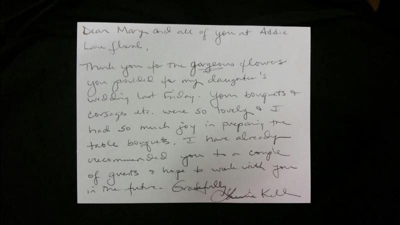 Handwritten note on white paper, photographed on a dark background.