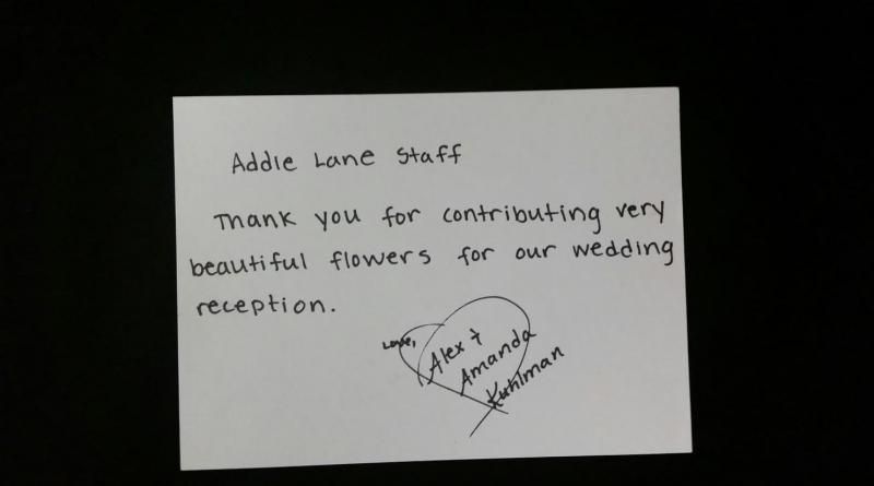 Handwritten thank-you note on white paper for beautiful flowers at a wedding reception.