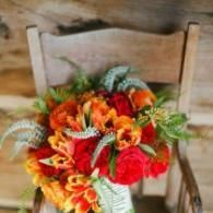 Bright orange and red flower bouquet on a wooden chair