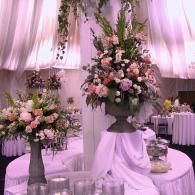 Elegant pink floral arrangements on draped tables in a softly lit event venue