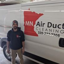 A man is standing in front of a mn air duct cleaning van.