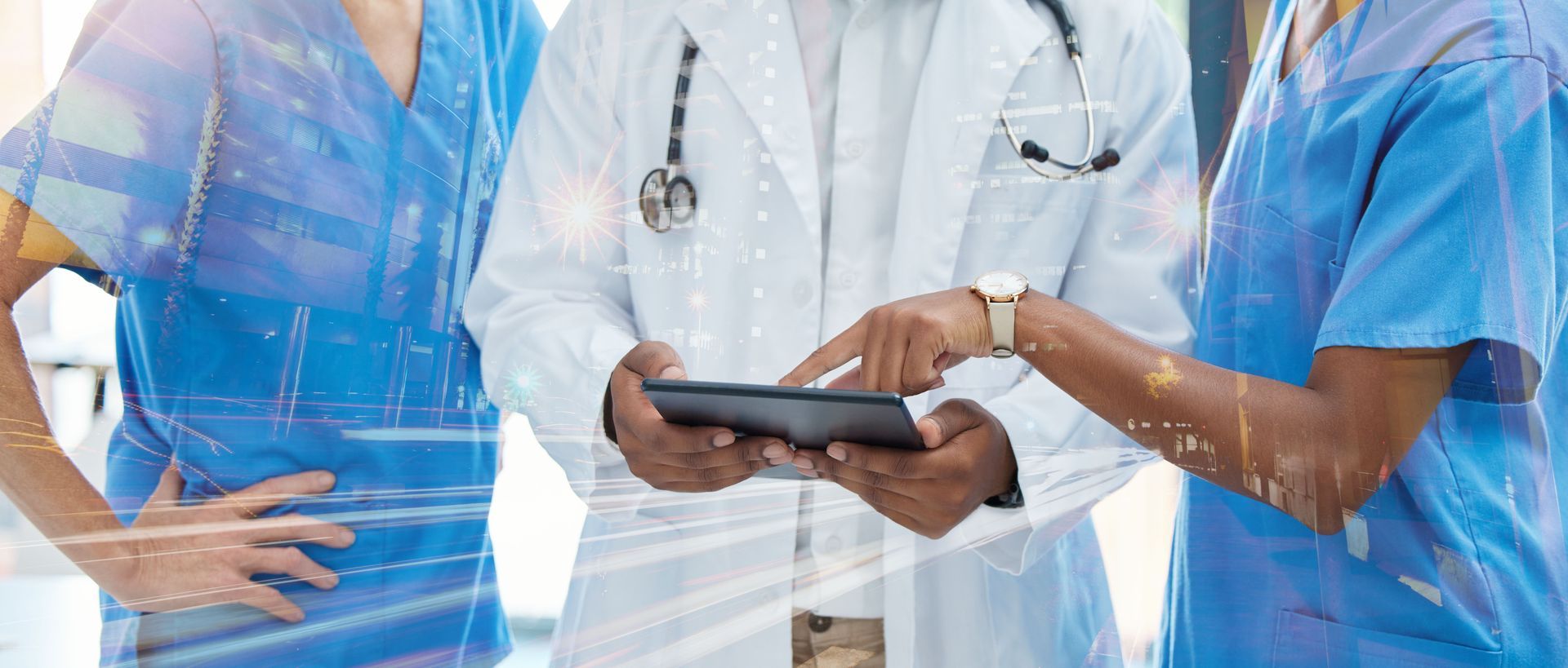 Medical professionals in scrubs and a lab coat reviewing a tablet.