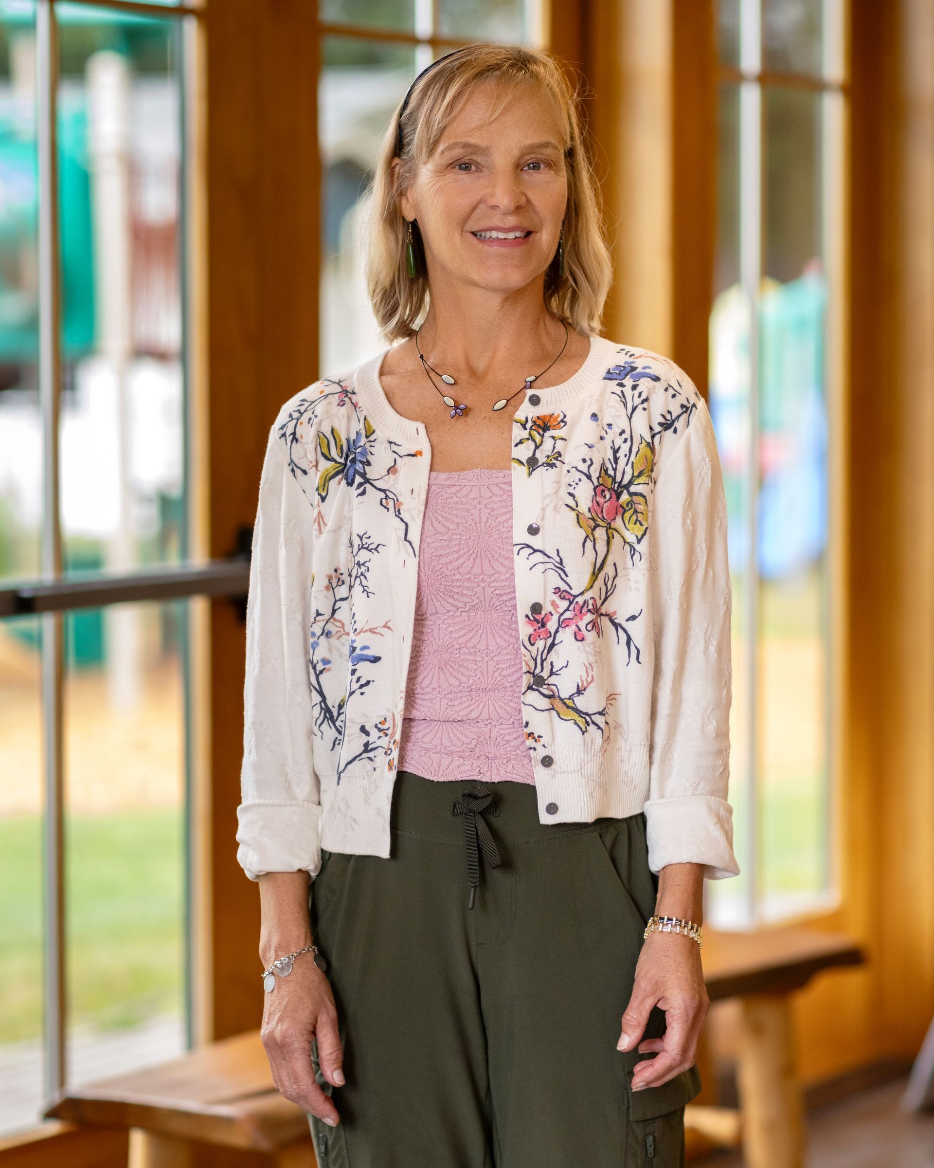 A photo of Heidi Holderied smiling indoors in a pink shirt and white sweater.
