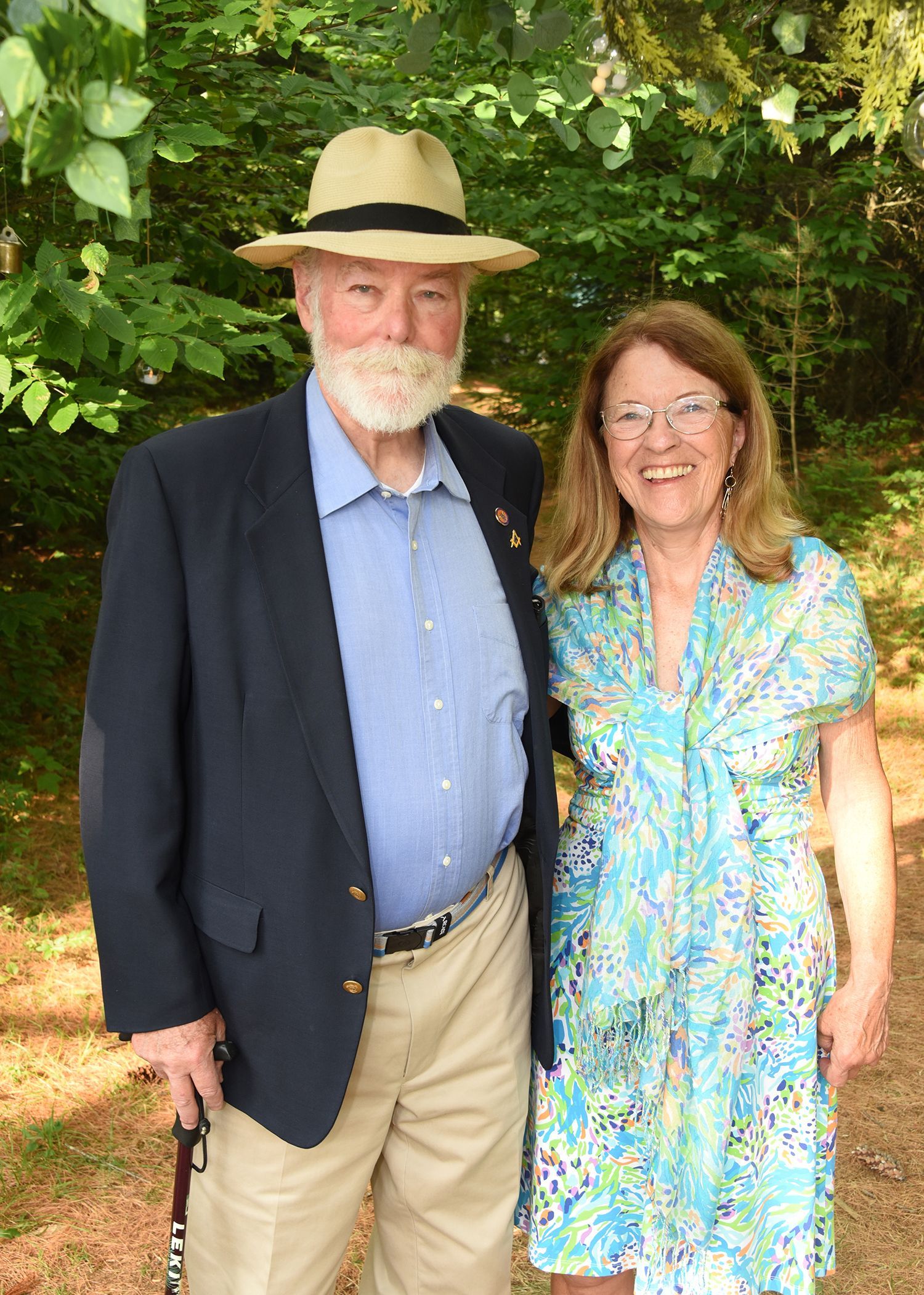 An older man with a white beard and a woman stand together outdoors. 